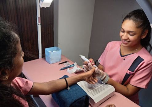 A Lights Up nailist smiling as she works on a guest's nails