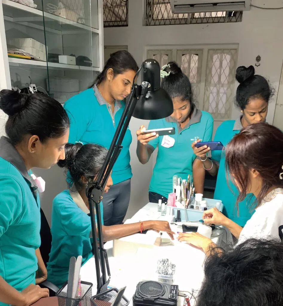Trainees gathered around a nail table watching a demonstration