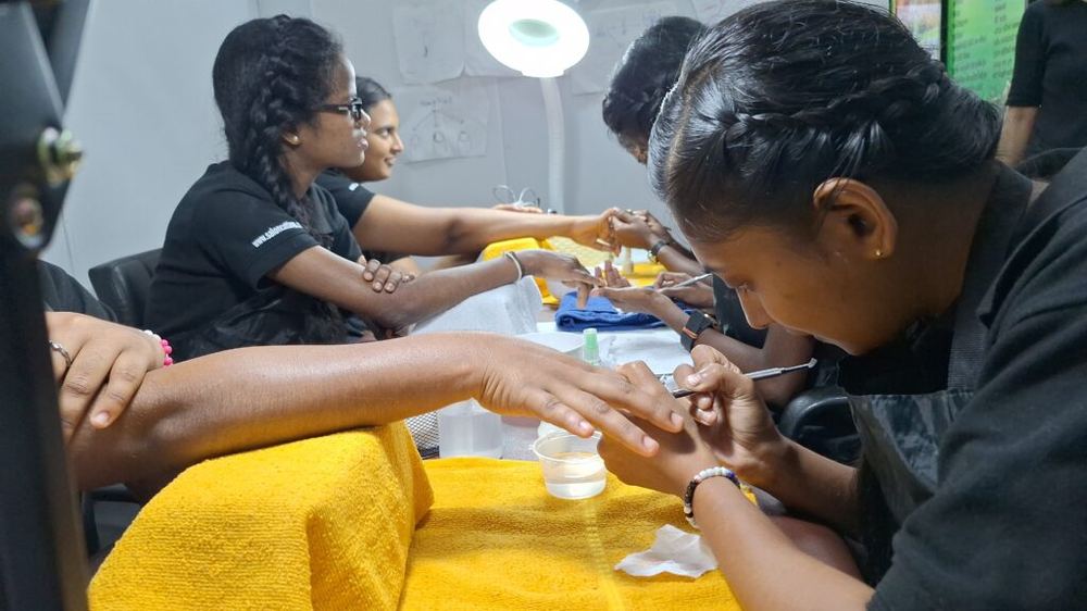 Trainees practising manicures on each other in the training room